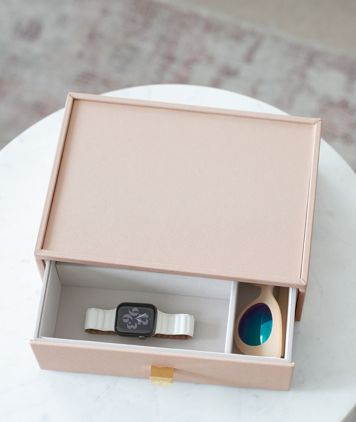 Smartwatch with a white band and glaases in a pink box on a white surface.