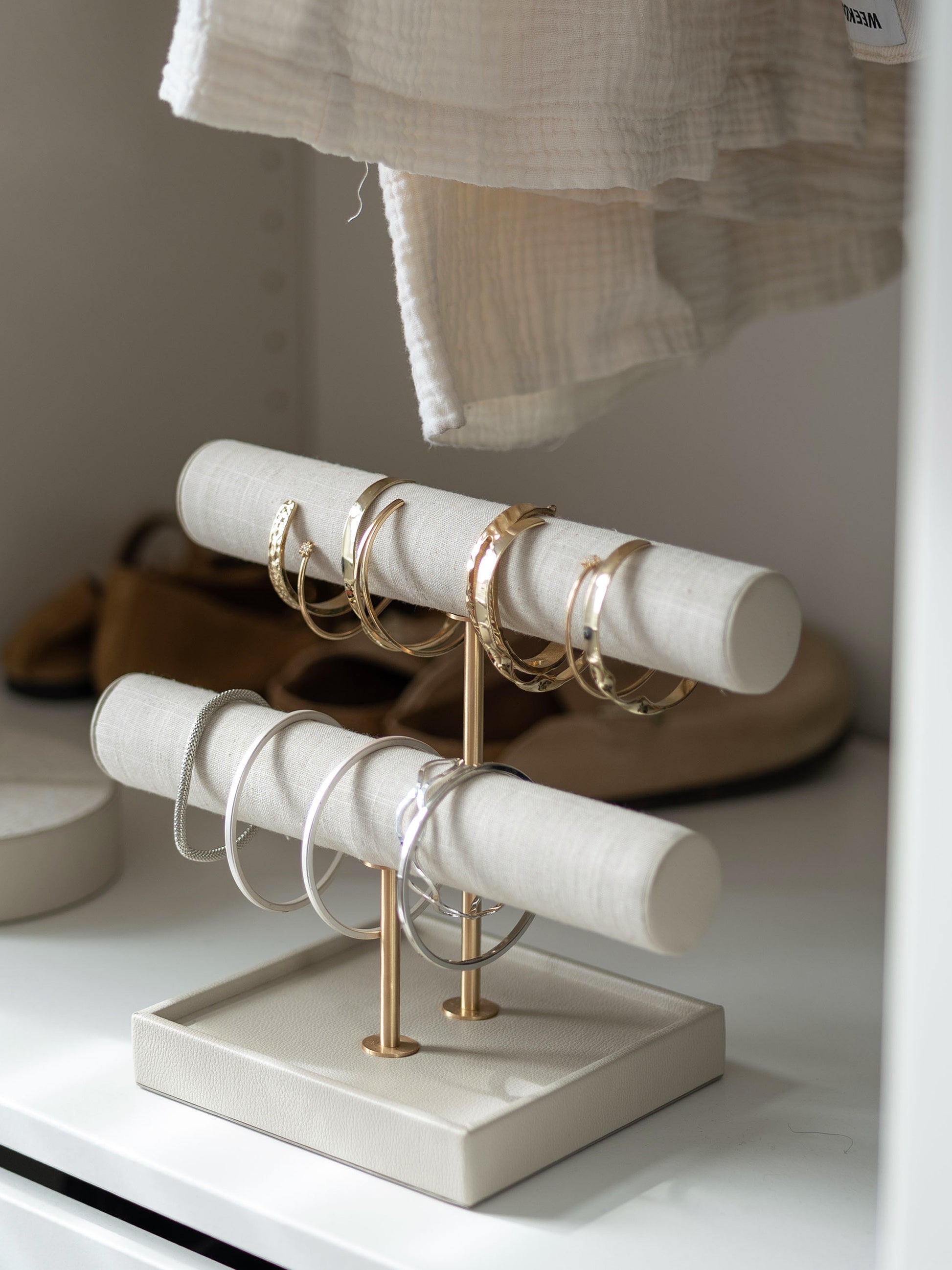 Oatmeal and linen jewelry display stand with rings and bangles on display inside a closet