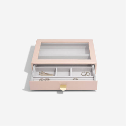 Pink jewelry box with jewelry items on a light gray background