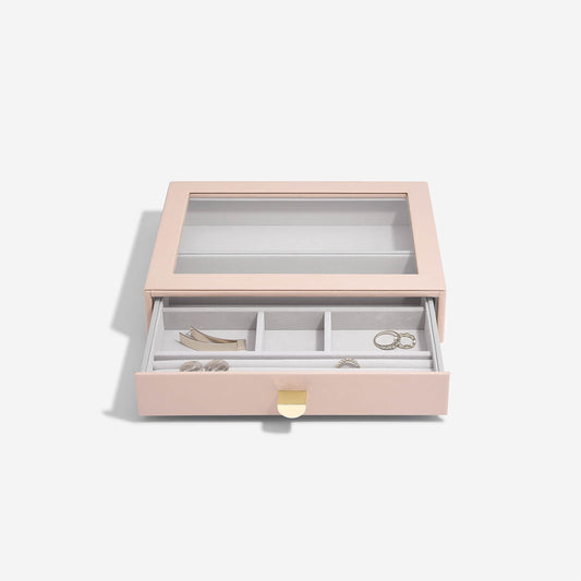 Pink jewelry box with jewelry items on a light gray background