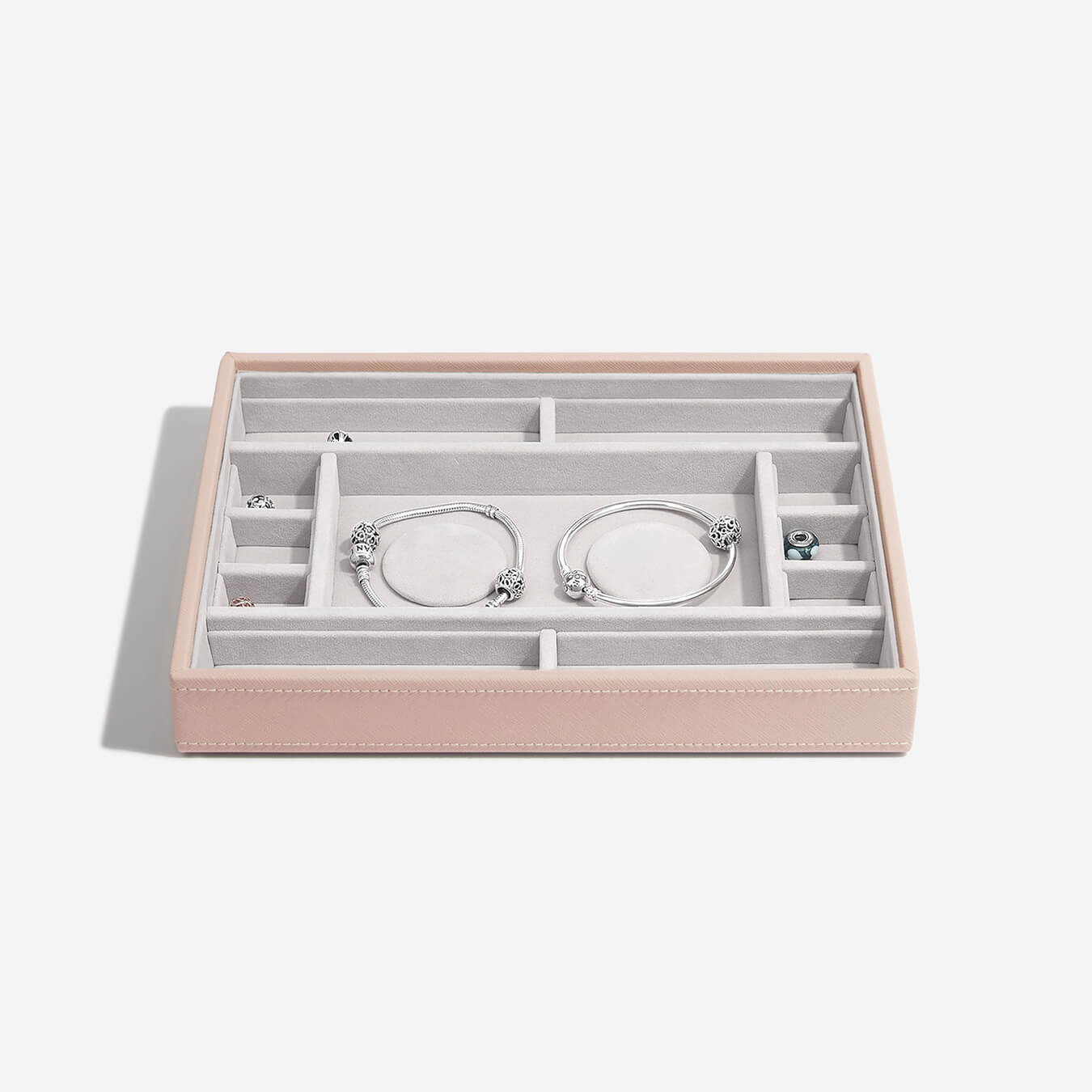 Pink jewelry box with silver bracelets on a white background