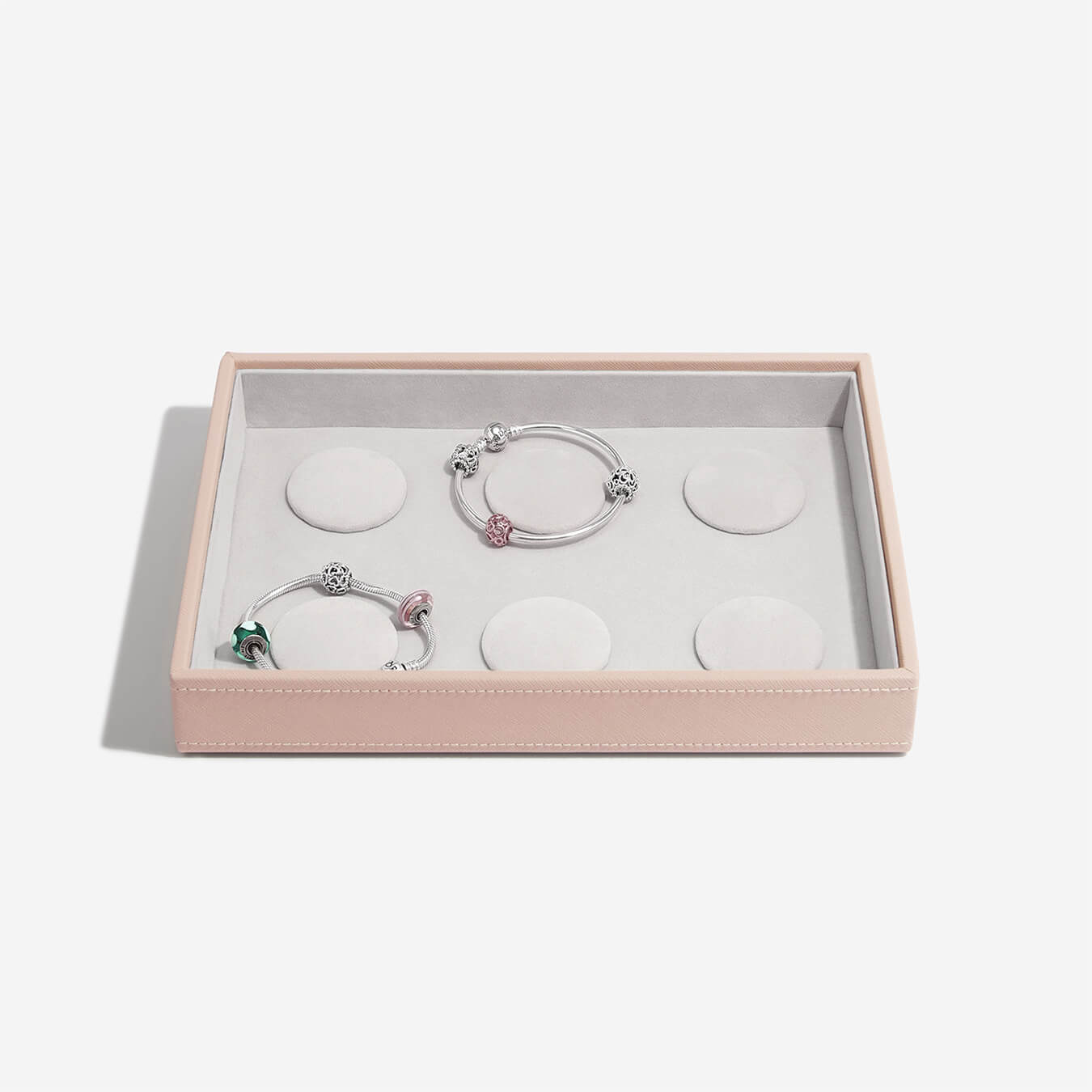 Two silver bracelets with pink accents in a pink jewelry box on a white background