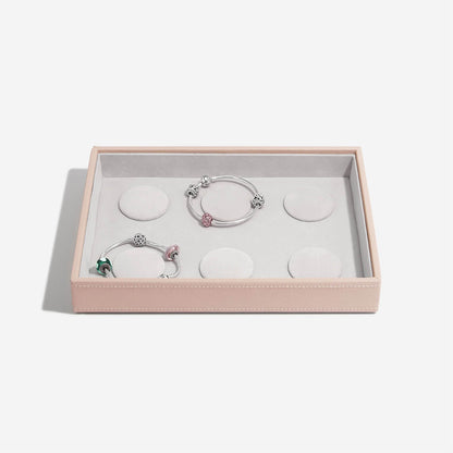 Two silver bracelets with pink accents in a pink jewelry box on a white background
