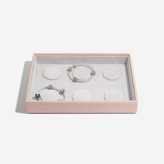 Two silver bracelets with pink accents in a pink jewelry box on a white background