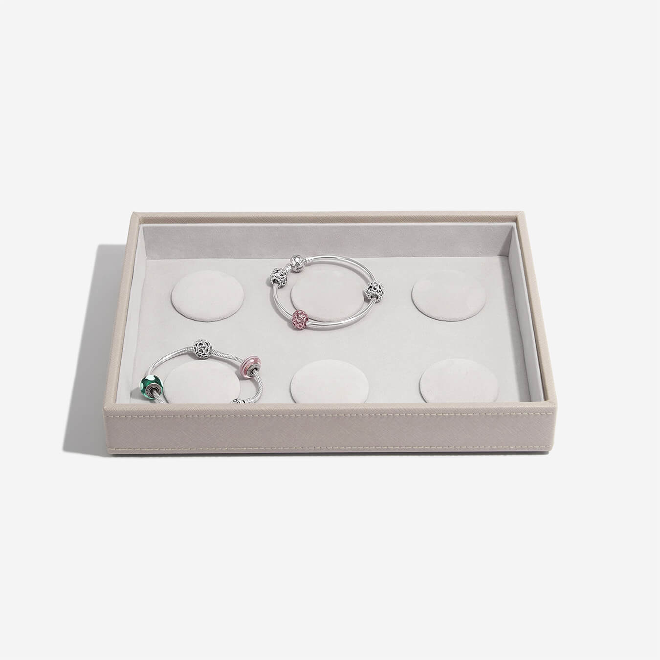 Two silver bracelets with charms in a box on a light gray background