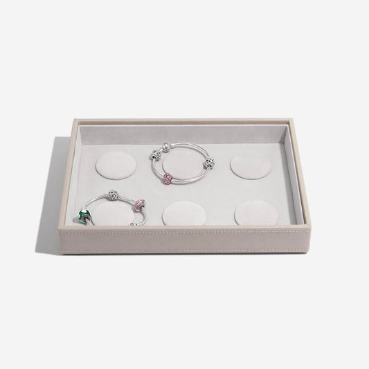 Two silver bracelets with charms in a box on a light gray background