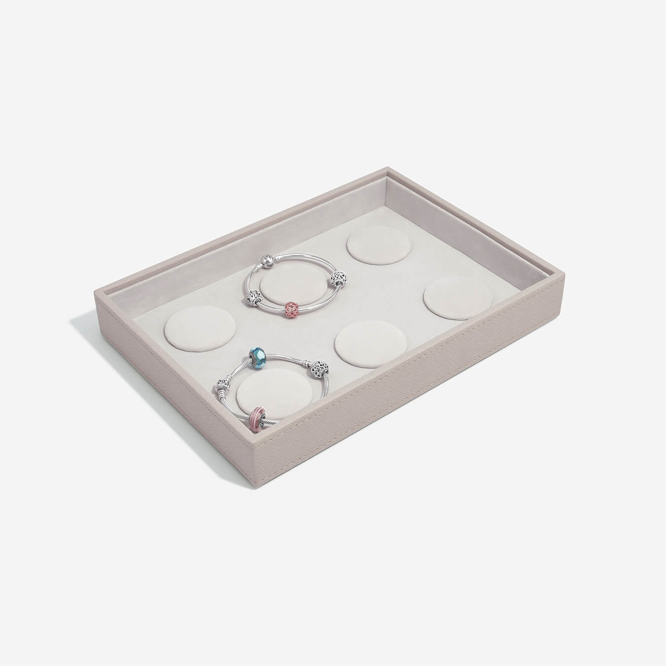 Two silver bracelets with colorful beads in a taupe jewelry box on a white background