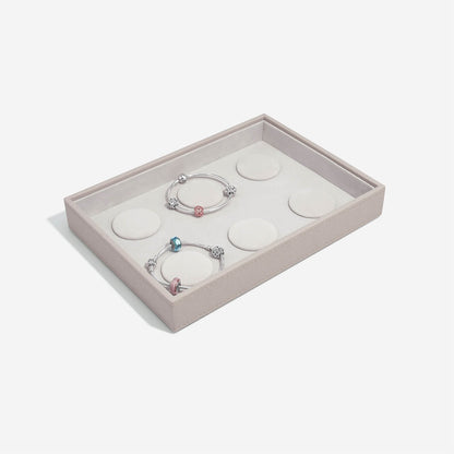 Two silver bracelets with colorful beads in a taupe jewelry box on a white background